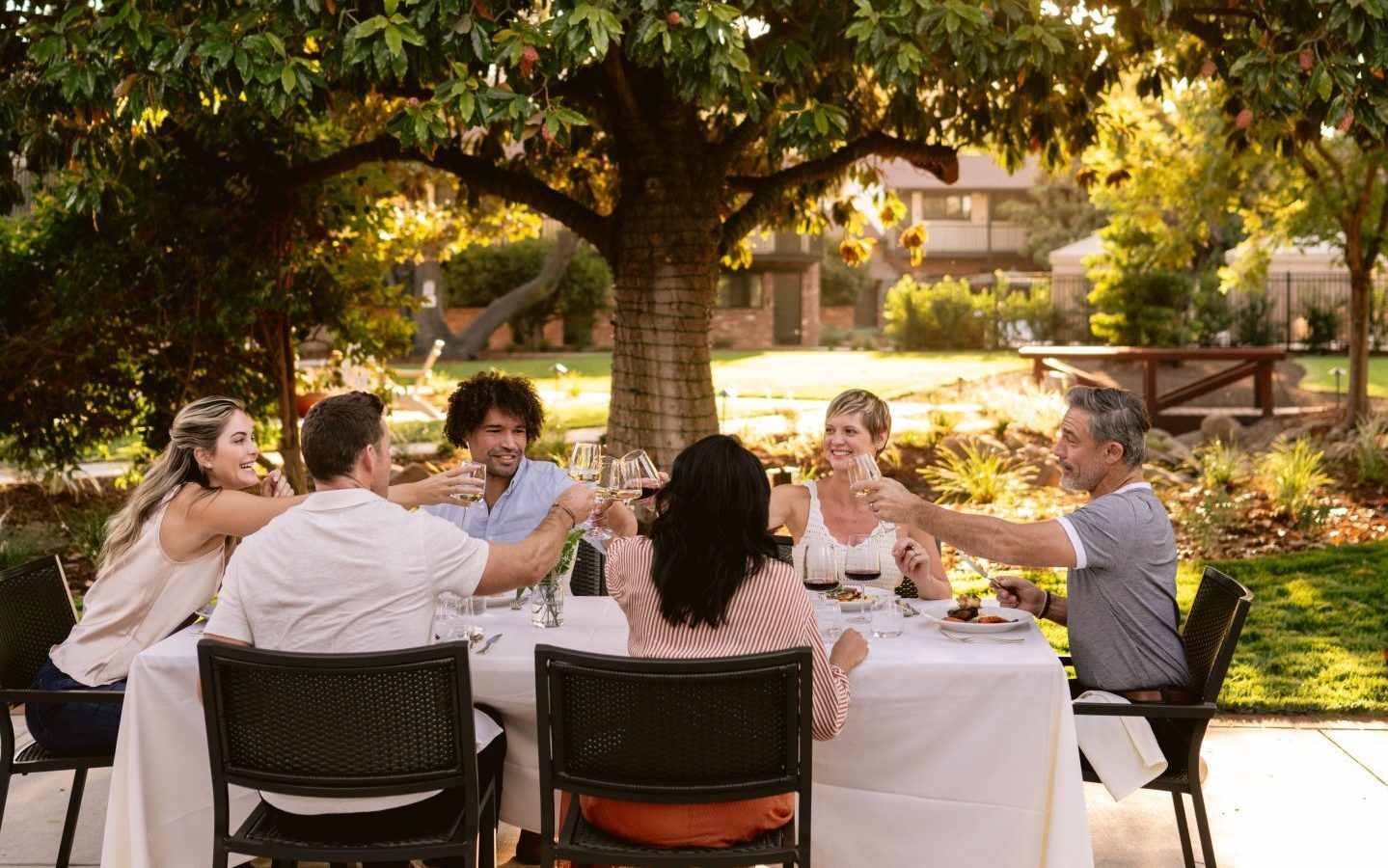 Group of people dining in a garden at golden hour.