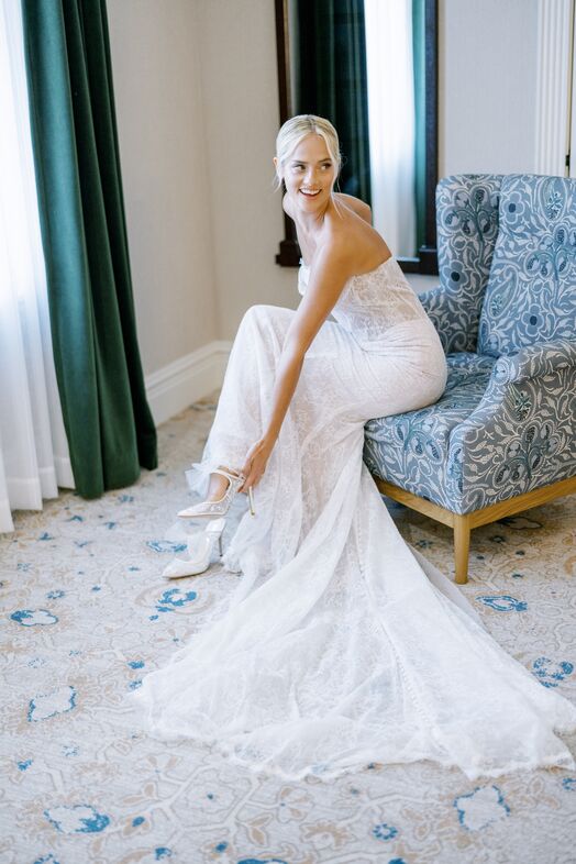 Women in white wedding dress sitting in blue floral chair
