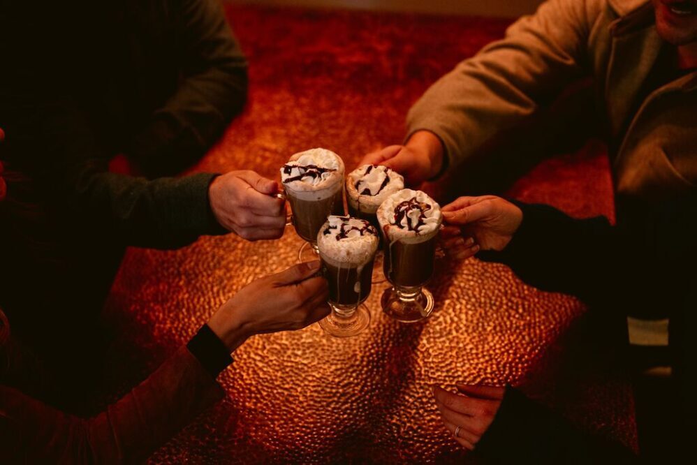 four hands holding hot chocolate