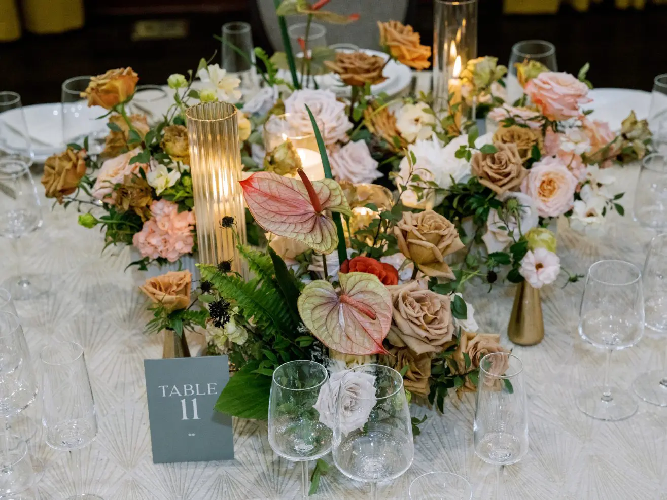 Colorful flower arrangement on a wedding dinner table with a "number 11" table sign.